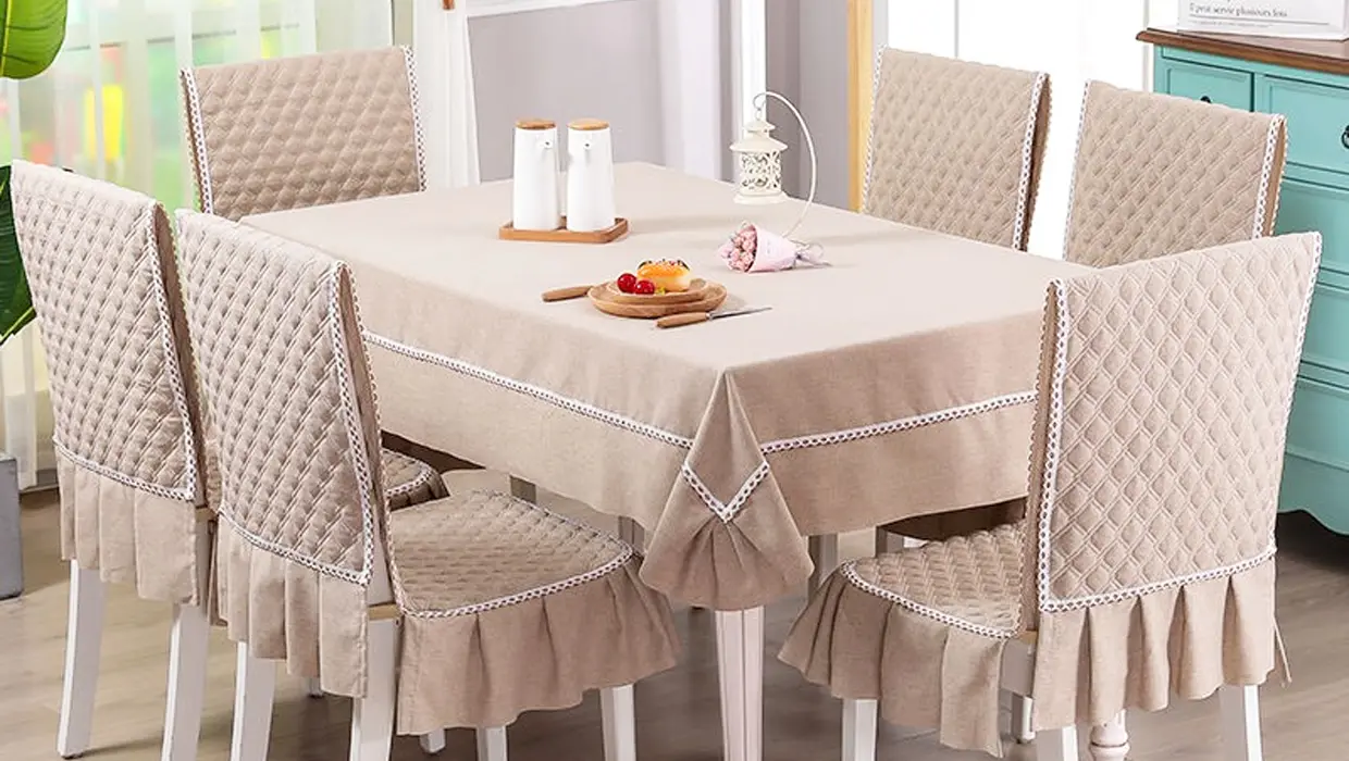 Gedeckter Esstisch mit beiger Tischdecke und passenden Stuhlhussen